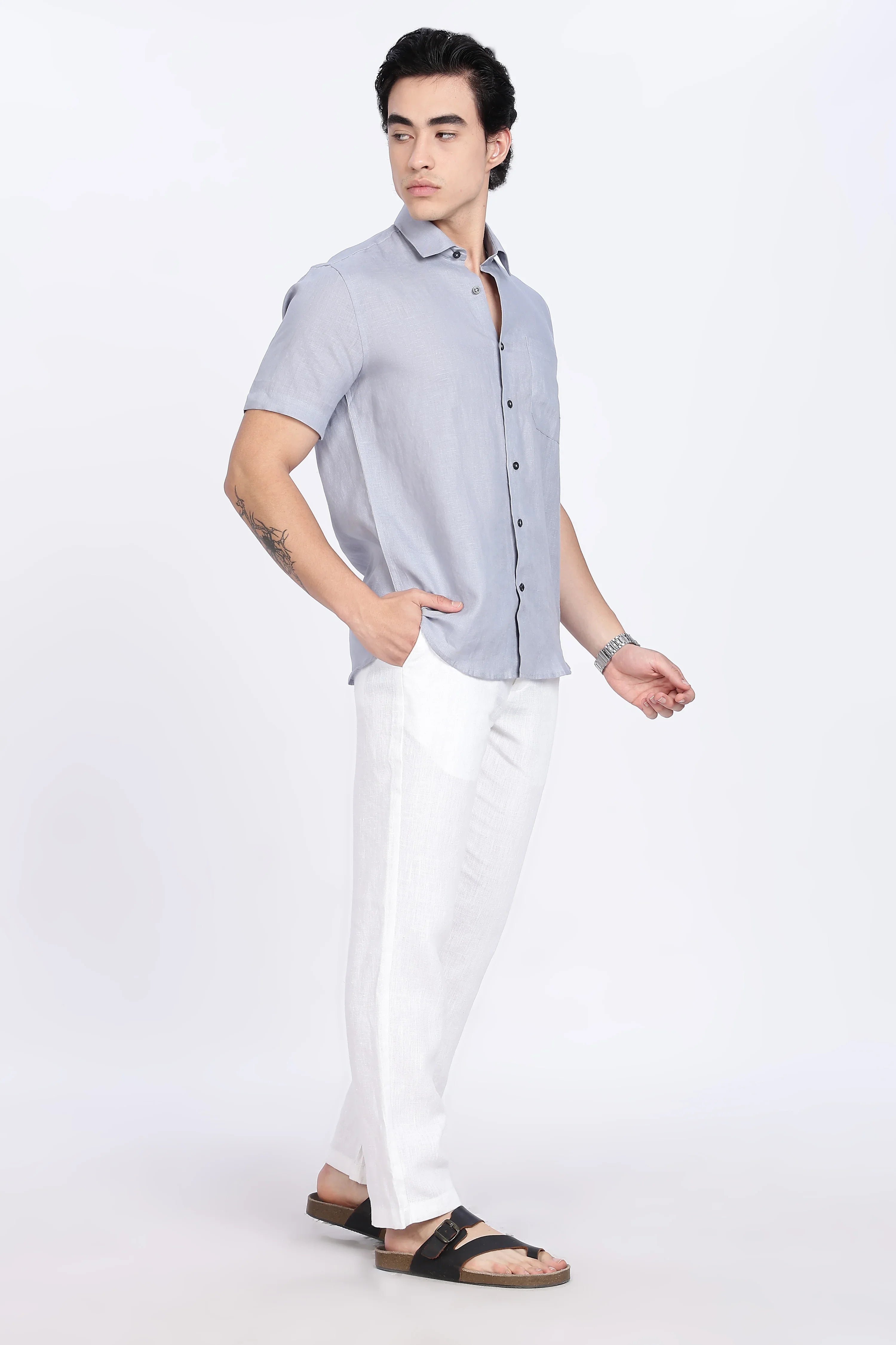 Man wearing a light gray short-sleeve shirt and white pants on a white background